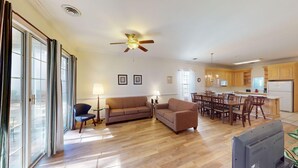 A spacious living area with a sofa, a television, and a dining table with chairs. - Four Bedroom, 3 Baths, Avian Forest, Scenic View (Pawleys Island)