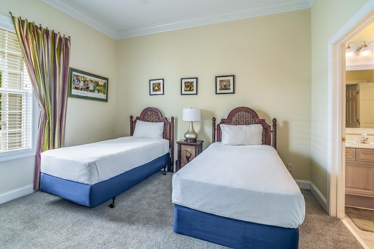 Habitació d'hotel amb dos llits individuals, una petita taula de nit amb una làmpada i una finestra amb cortines.