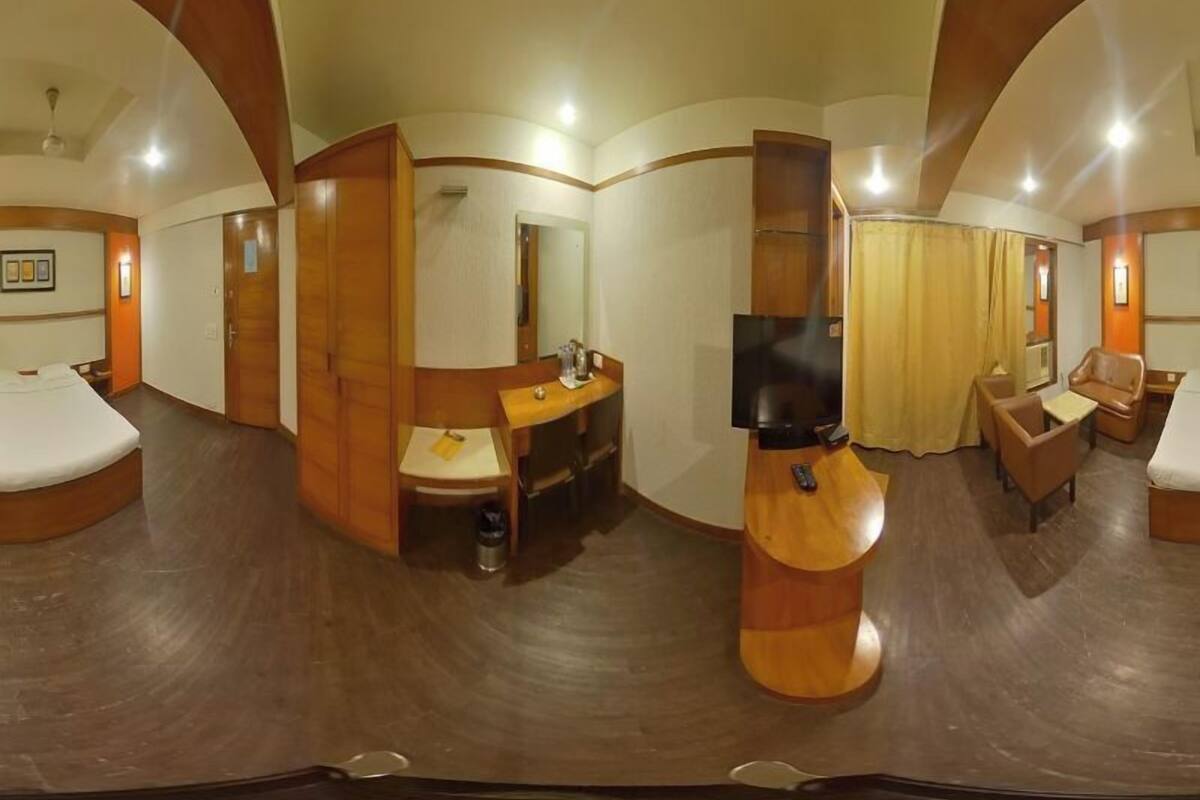 A hotel room with a bed, a desk, a chair, a TV, and a bathroom.