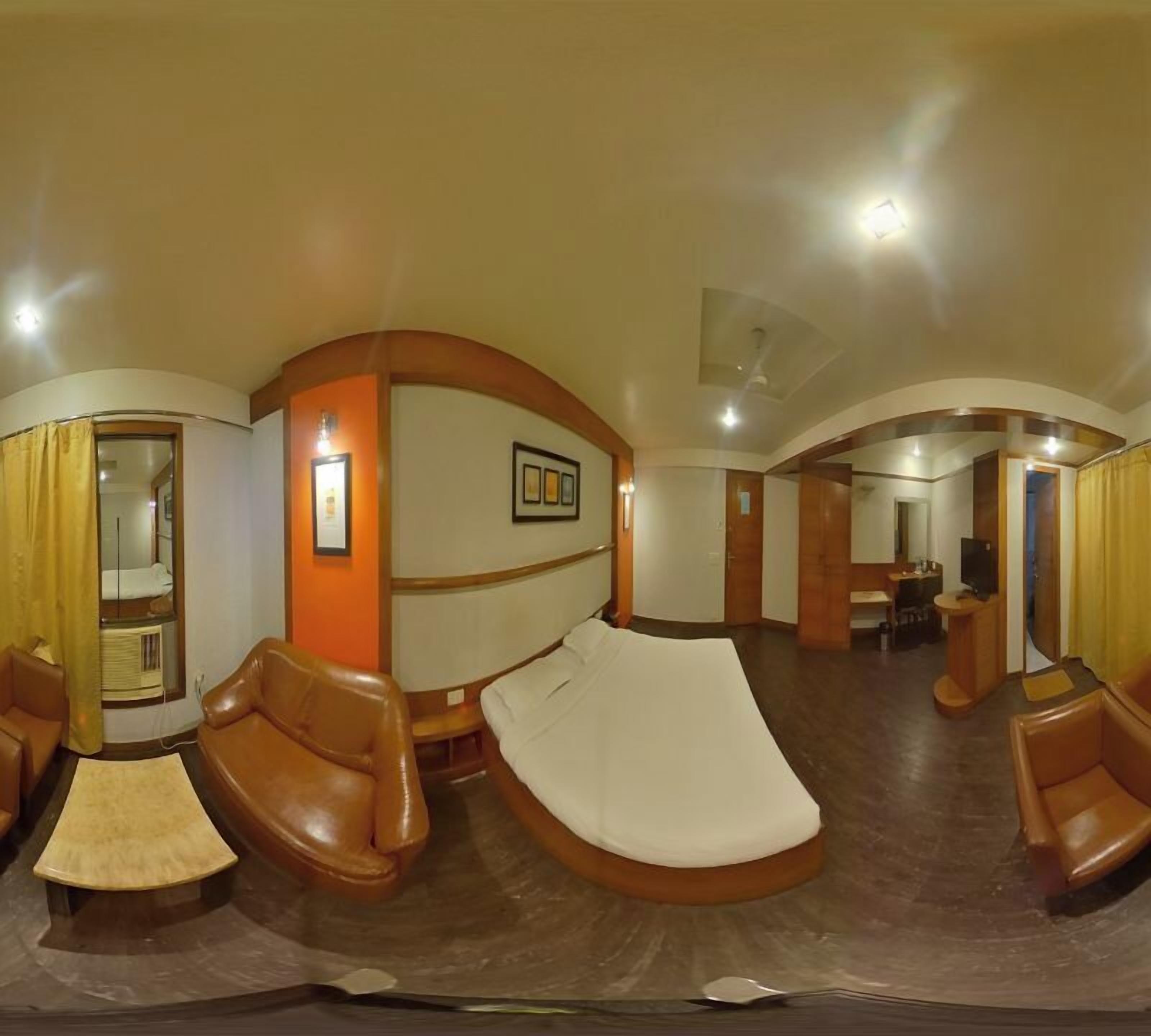 Una stanza con disposizione ad arco, un divano, un letto e un piccolo tavolo.