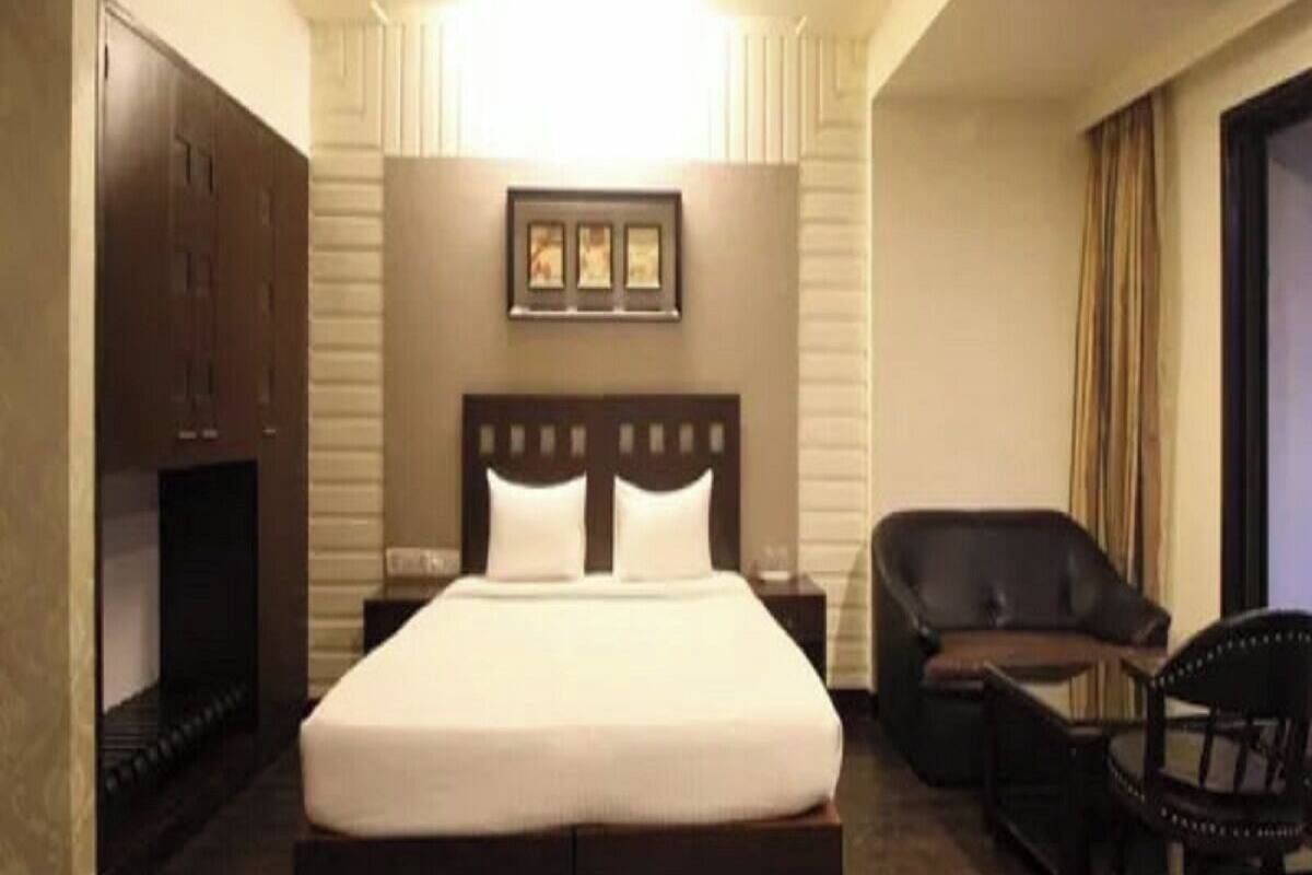 A hotel room with a large bed, a desk, a chair, and a ceiling fan.