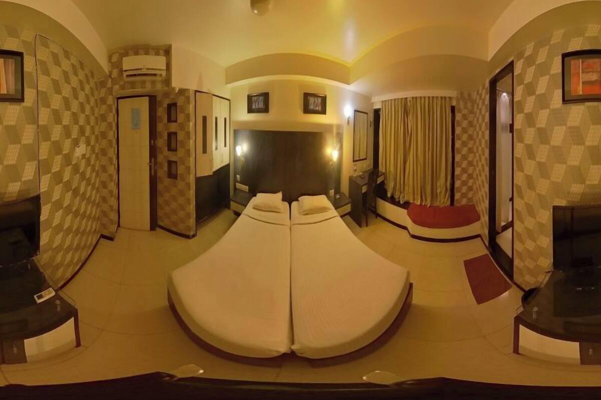 A room with a large bed, a desk, a chair, and a ceiling fan.