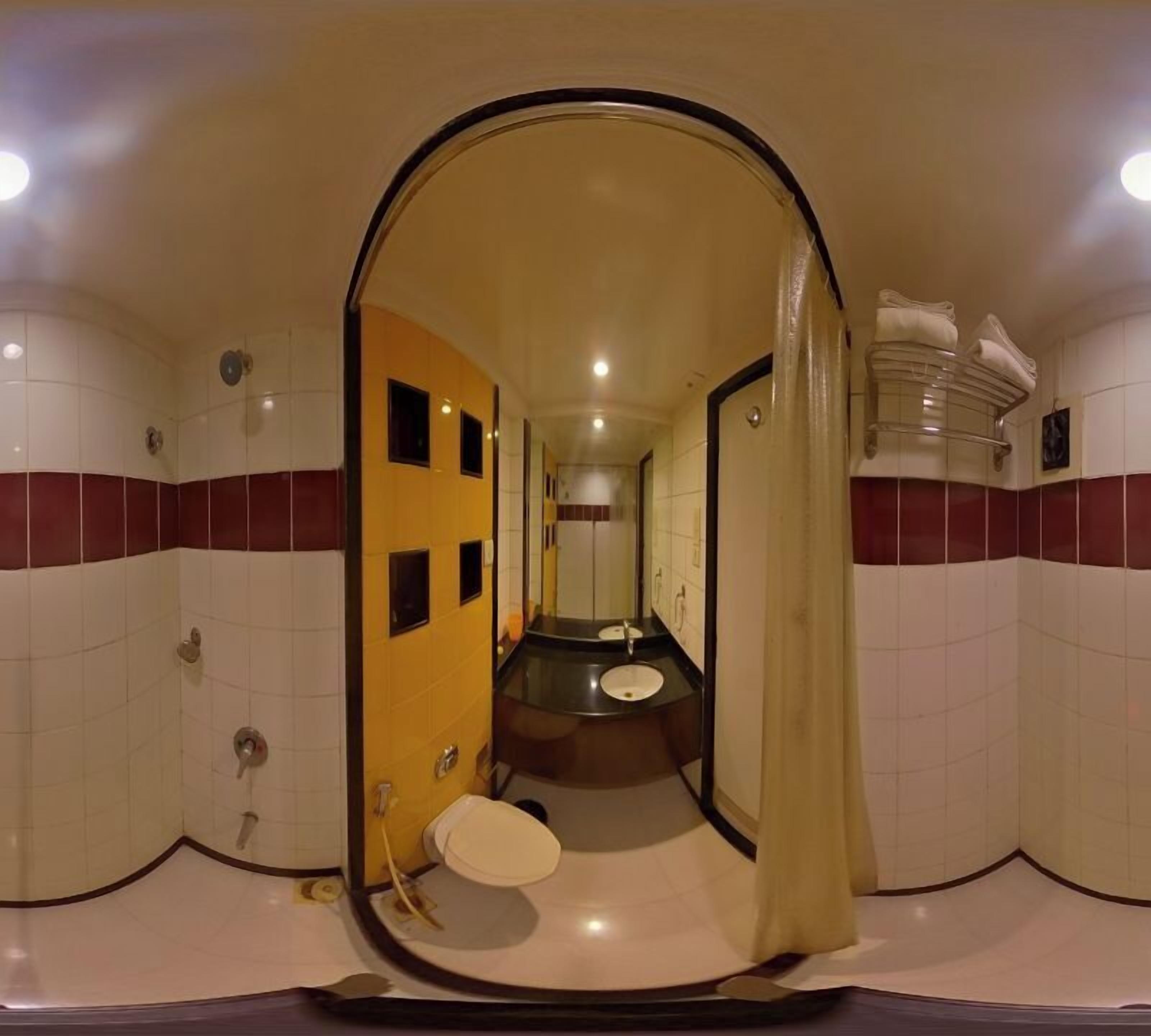 A bathroom with a yellow wall, a white toilet, and a sink.