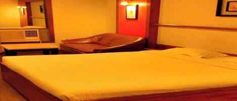 A hotel room with a large bed, a desk, and a chair.