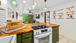 A kitchen with a wooden countertop, a built-in stove, and a green cabinet.