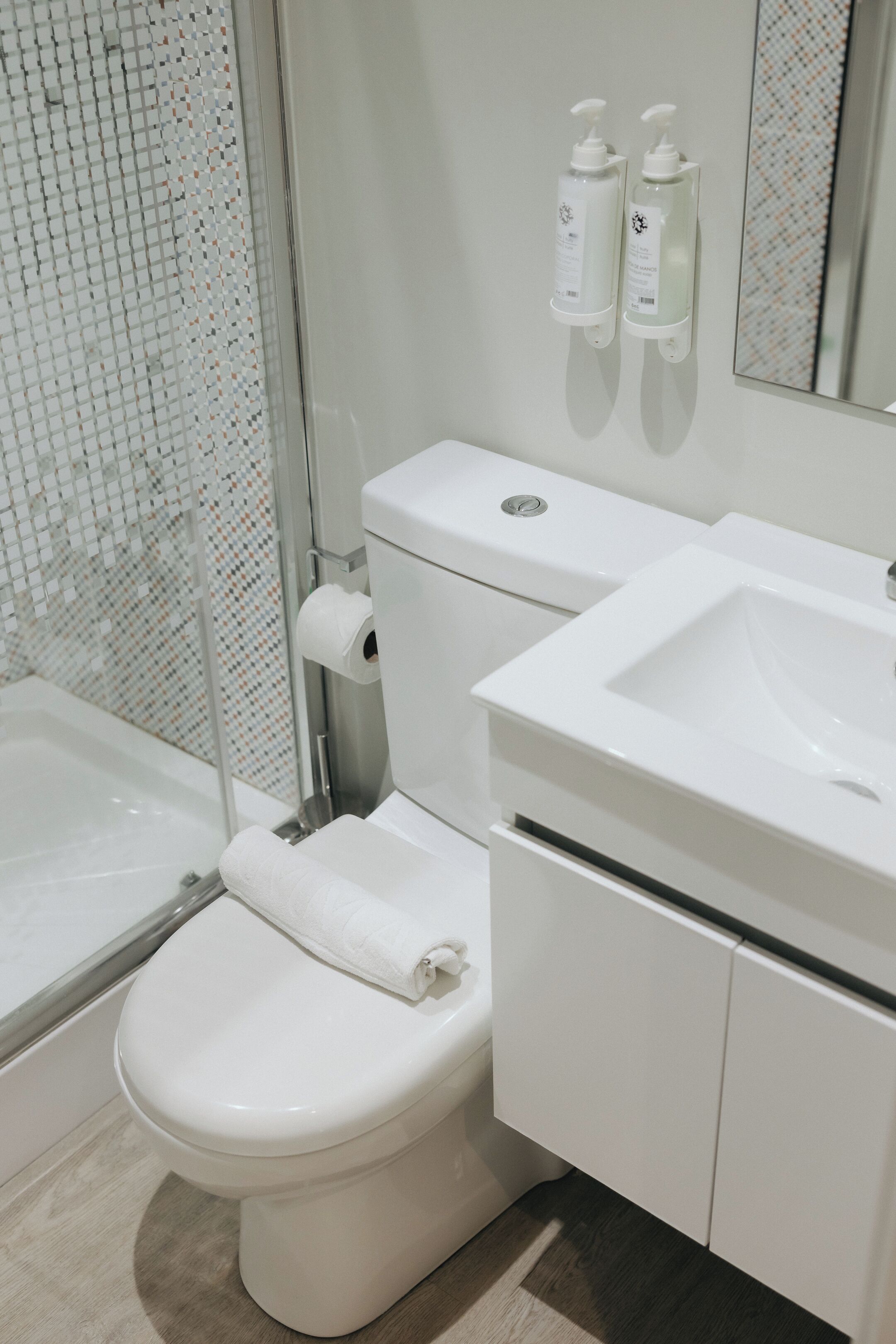 A modern bathroom with a toilet, sink, and shower.