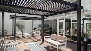 A covered outdoor seating area with white furniture and potted plants. - M’AR De AR Auria (Lisbon)