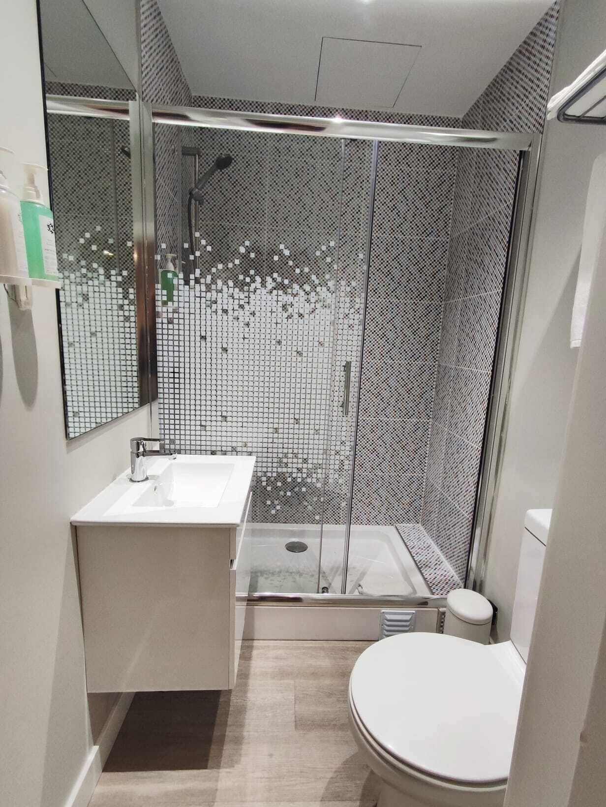 A modern bathroom with a glass-enclosed shower, a white sink, and a toilet.