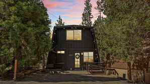 A black cabin with a large window, a door with a wreath, and a number '42703' on the wall. - 2BR Retreat: EV, Hot Tub, BBQ & Dog-Friendly (Big Bear Lake)