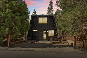 A black cabin with a large window, a door with a wreath, and a number '42703' on the wall. - 2BR Retreat: EV, Hot Tub, BBQ & Dog-Friendly (Big Bear Lake)