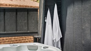 A hot tub with a wooden deck and a black door with white towels hanging on it. - 2BR Retreat: EV, Hot Tub, BBQ & Dog-Friendly (Big Bear Lake)