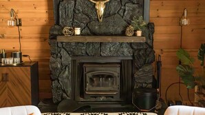 Una chimenea rústica con pared de piedra y decoración de cabeza de toro.