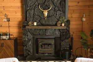 Une cheminée rustique avec un mur en pierre et une décoration représentant une tête de taureau.