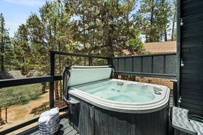 A hot tub on a deck with a view of trees and a building in the background.