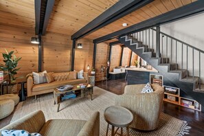 A modern interior with a wooden ceiling, a staircase, a sofa, and a coffee table.