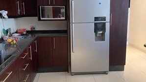 A modern kitchen with dark wooden cabinets, a stainless steel refrigerator, a microwave, and a water dispenser. - Hush Guest House (Thabazimbi)