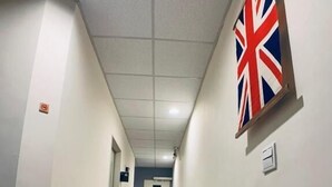 A hallway with a wooden floor, white walls, and a British flag on the right. - Lazy Bone (Hsinchu)