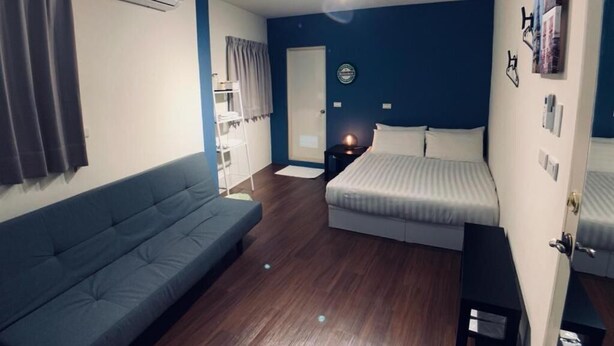 A bedroom with a bed, a sofa, a wardrobe, and an air conditioning unit. - Lazy Bone (Hsinchu)