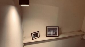 A staircase with a wooden handrail and a white wall. There are two framed pictures on the wall above the staircase. - Lazy Bone (Hsinchu)