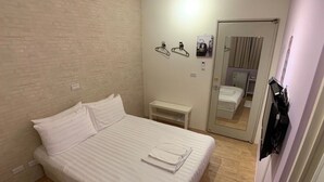 A hotel room with a bed, a small bedside table, a mirror, and a door leading to a bathroom. - Lazy Bone (Hsinchu)