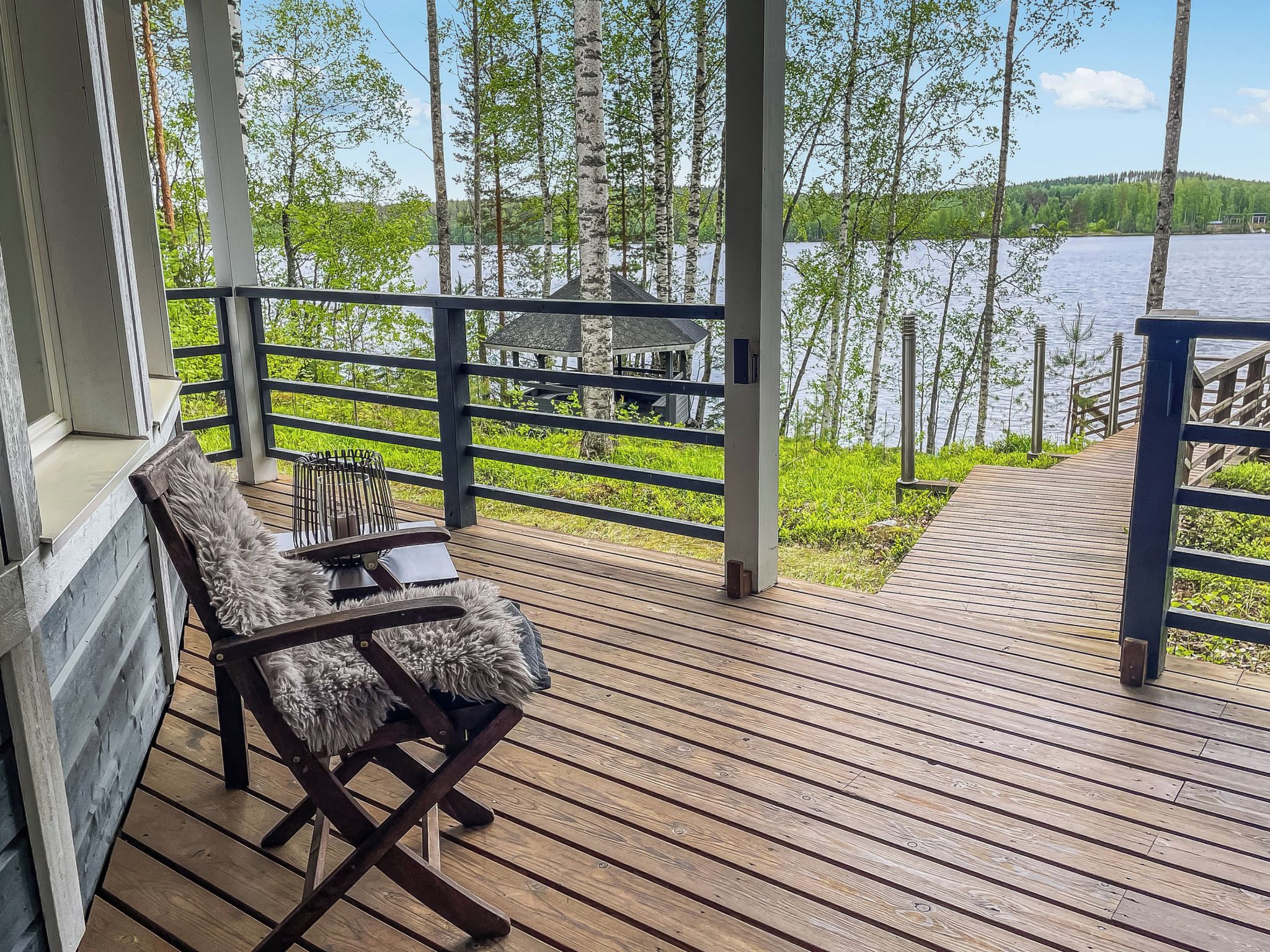 Une terrasse en bois avec une chaise et une vue sur un lac et des arbres.
