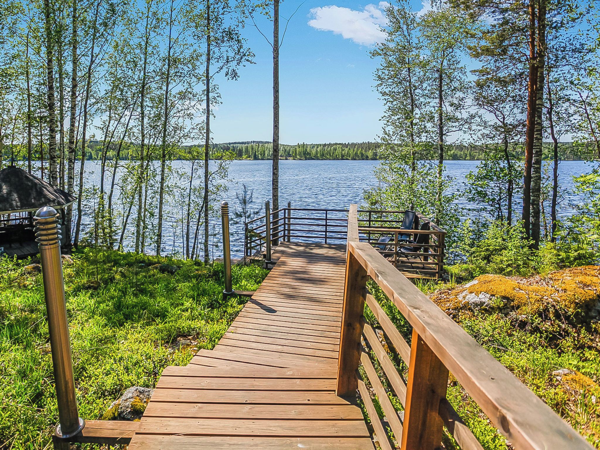 Eine Holzterrasse, die zu einem See führt, mit Blick auf Wasser und Bäume.