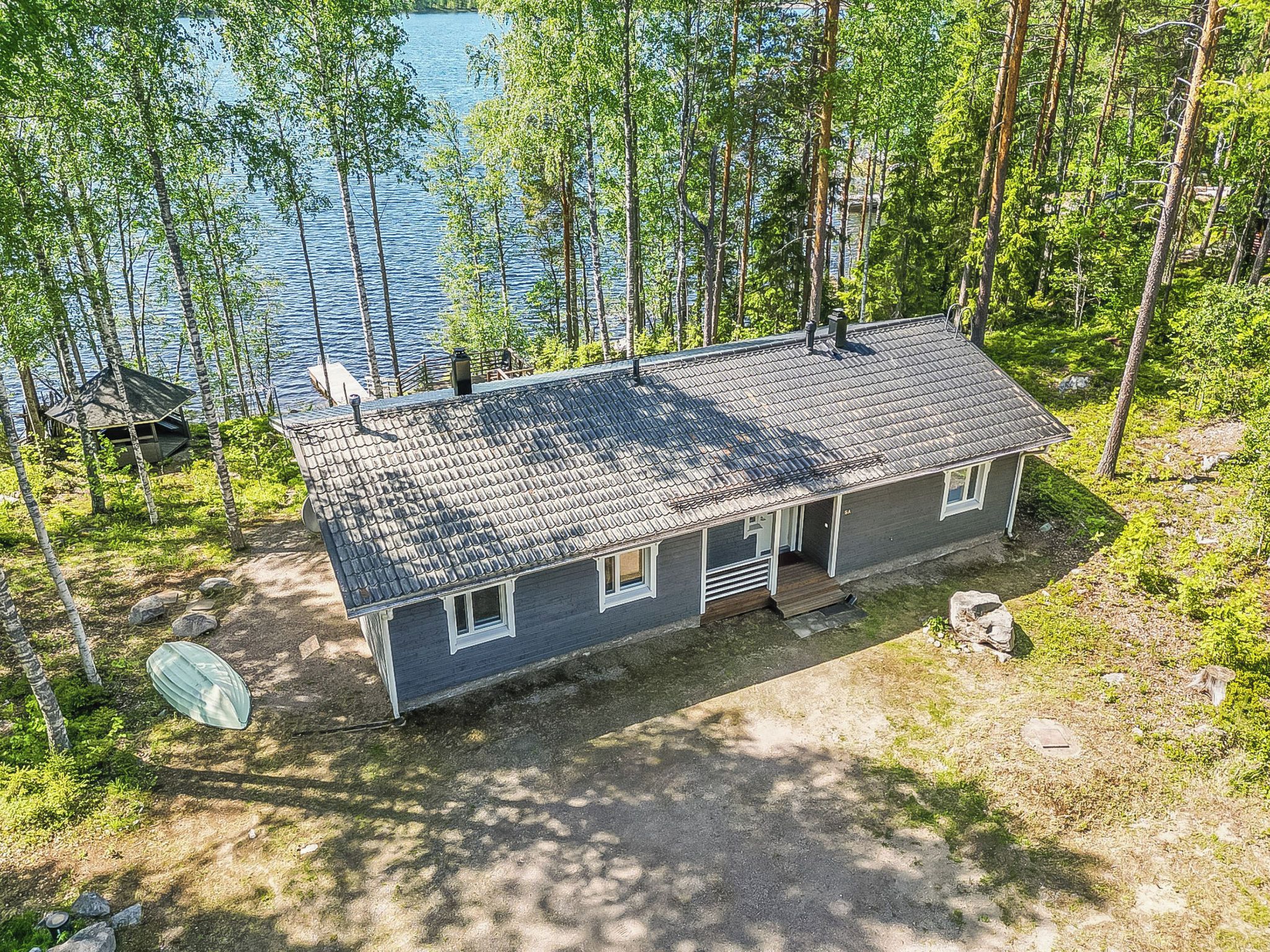 Une cabane avec un toit en pente, une véranda à l’avant et une jetée qui s’avance dans un lac.