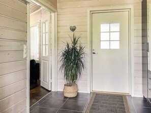 Un couloir avec une porte, une plante en pot et un tapis.