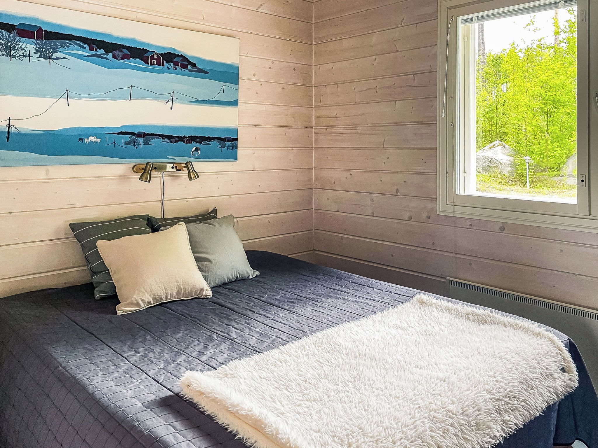 A room with a bed, a painting, and a window.