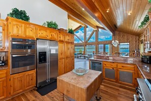 A spacious kitchen with wooden cabinetry, stainless steel appliances, and a large island.