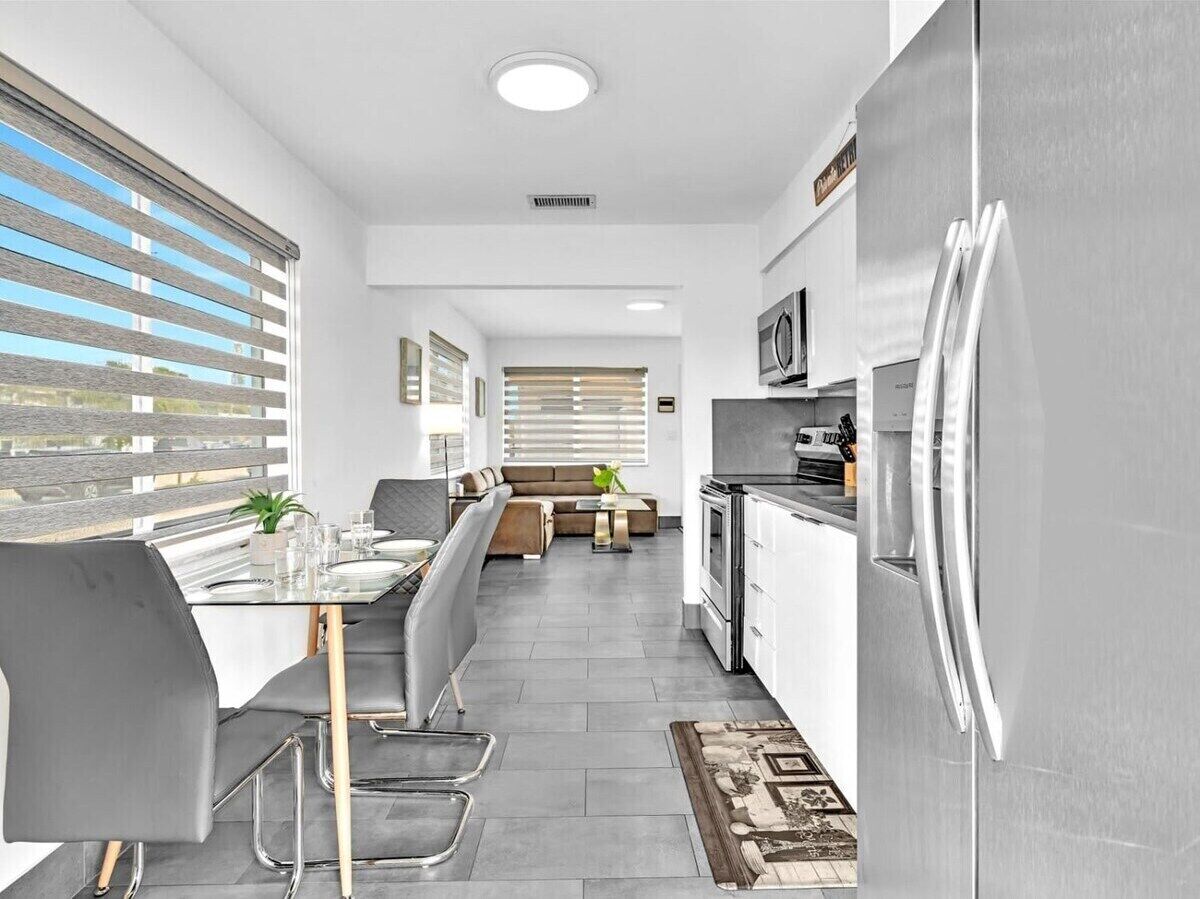 A modern kitchen with a dining area, a built-in oven, and a refrigerator.