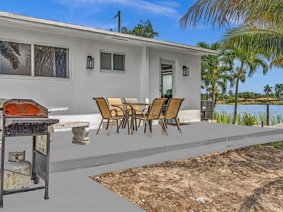 A modern house with a patio, outdoor furniture, and a gas grill.