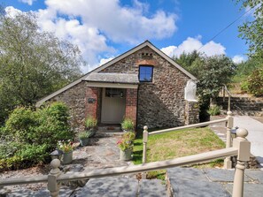 A stone cottage with a pitched roof, a small window, and a door. - Shipload Cottage (Bideford)