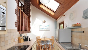 Een compacte keuken met een inbouwfornuis, een spoelbak en een eethoek met stoelen.