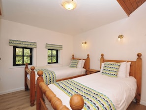 A bedroom with two beds, wooden headboards, and a ceiling light fixture.
