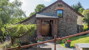 A stone building with a wooden door, a small window, and a staircase leading up to the entrance. - Shipload Cottage (Bideford)