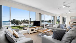 Un salón amplio con una televisión grande, asientos cómodos y vistas al exterior.