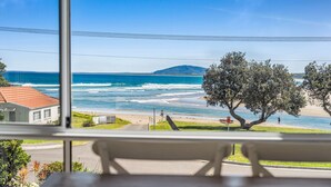 Vista de una playa con olas, un árbol y un banco.