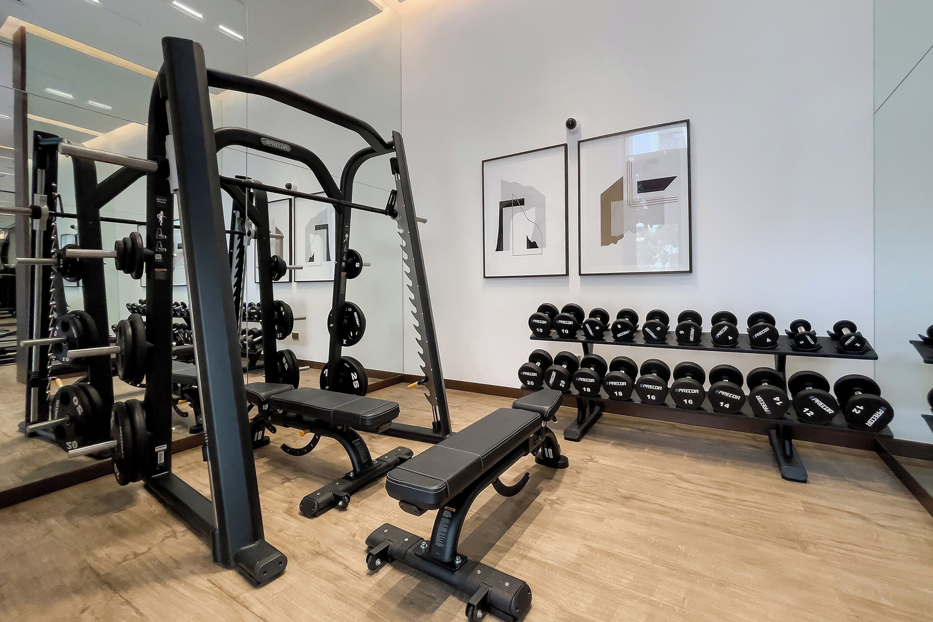 A gym with weightlifting equipment, benches, and a rack of dumbbells.