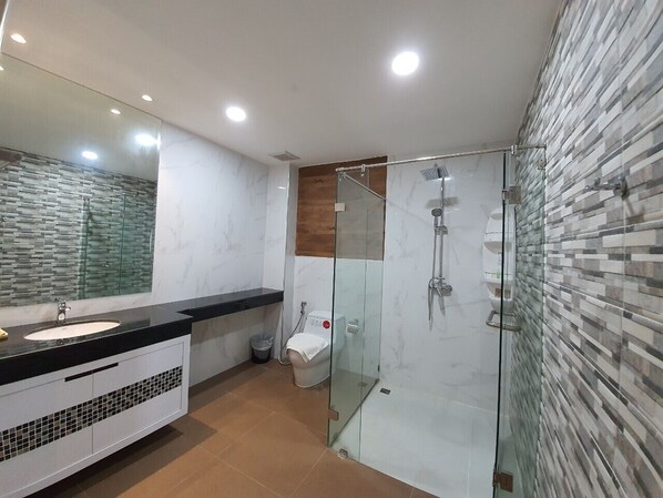 A modern bathroom with a glass-enclosed shower, a white sink, and a mirror above it. - Soidao Goodview Resort (Pong Nam Ron)