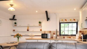 A modern kitchen with a microwave, stove, and a window with a view. - Windbury Cottage (Bideford)