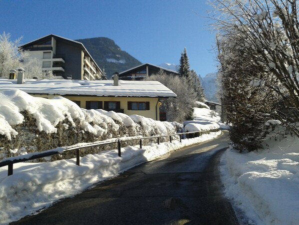 A snow-covered road with buildings on either side, including a hotel with a mountain view.