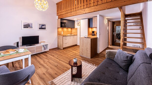 Un appartement moderne doté d’un espace de vie aménagé dans un style « loft », d’une cuisine et d’un coin repas.