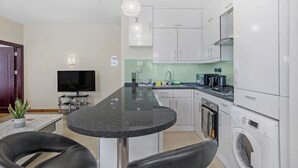 A modern kitchen with a central island, built-in appliances, and a flat-screen TV. - Luxury Mayflower Apartment, Central City Centre, Newly Refurbished (Plymouth)