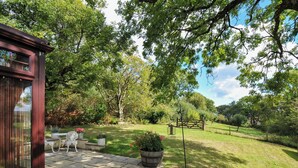 A patio area with a stone floor, a wooden fence, and a view of a grassy field.