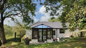 A house with a conservatory, a lawn, and a wooden fence.