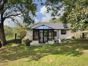 A house with a conservatory, a lawn, and a wooden fence. - Barley Cottage (Bideford)