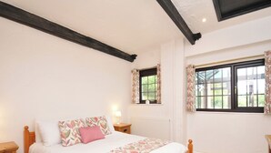 A bedroom with a wooden bed, a nightstand, a window with curtains, and a radiator.