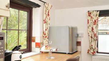 A kitchen with a Bosch appliance, a refrigerator, and a window with floral curtains.