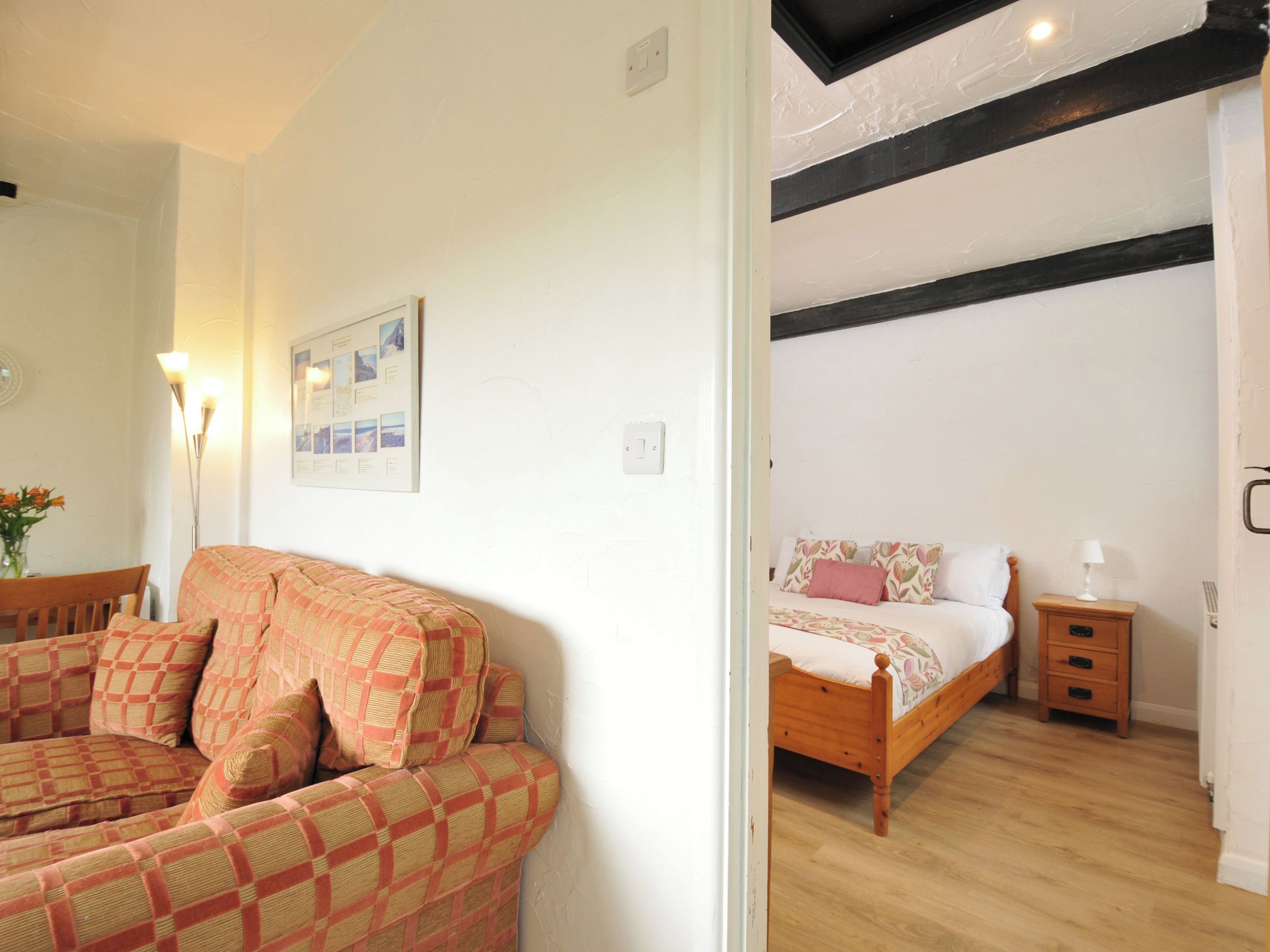A room with a wooden bed, a wooden nightstand, a bedside table, and a chair with a checkered cushion.